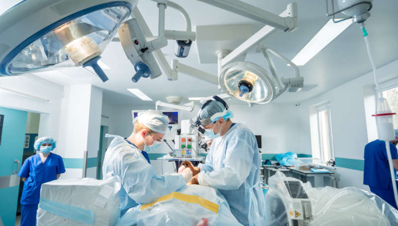 Spinal surgery. Group of surgeons in operating room with surgery equipment. Laminectomy